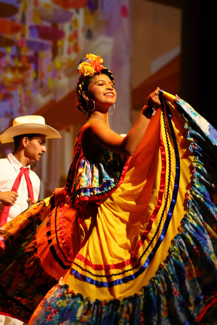 Folklórico dancer in a colorful yellow skirt performing on stage